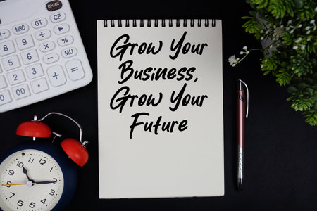 Grow Your Business, Grow Your Future text with calculator with alarm clock on black backgroundの写真素材