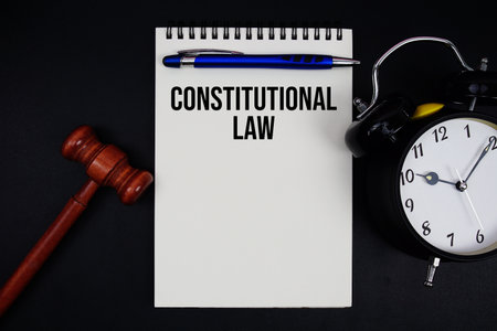 Constitutional Law text written on notepad with gavel and alarm clock on black backgroundの写真素材