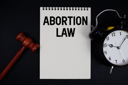 Abortion Law text written on notepad with gavel and alarm clock on black backgroundの写真素材