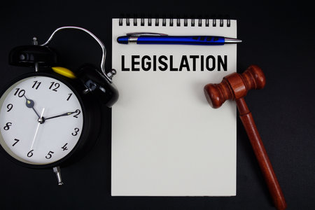 Legislation text written on notepad with gavel and alarm clock on black backgroundの写真素材