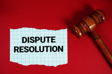Dispute Resolution text written on rip paper with wooden judgment gavel on red backgroundの写真素材