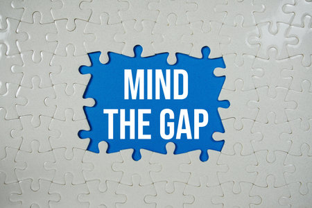 Jigsaw puzzle with a missing piece with "Mind The Gap" on blue backgroundの写真素材