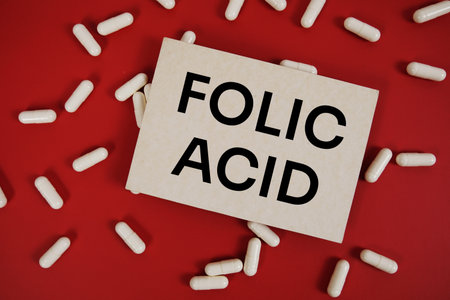 Folic Acid text written on paper card with medicine capsule on red backgroundの写真素材
