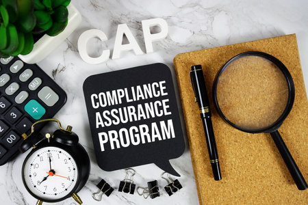 CAP - Compliance Assurance Program acronym with calculator, alarm clock and magnifying glass, business concept backgroundの写真素材