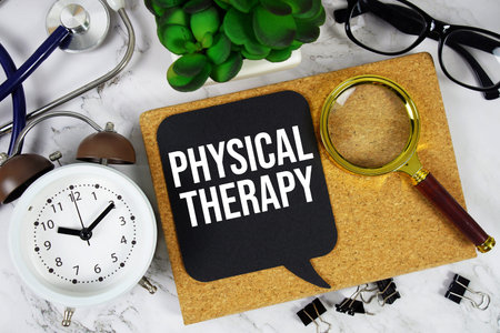 Physical Therapy text with alarm clock, calculator and stethoscope on marble background
