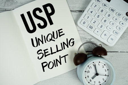 USP Unique Selling Point text on paper notebook page with alarm clock and calculator on wooden backgroundの写真素材