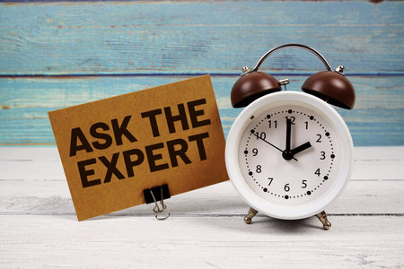 Ask The Expert text written on paper card with alarm clock on wooden backgroundの写真素材