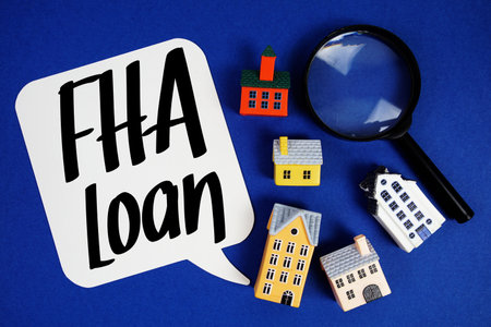 FHA Loan text with house models and magnifying glass on blue backgroundの写真素材