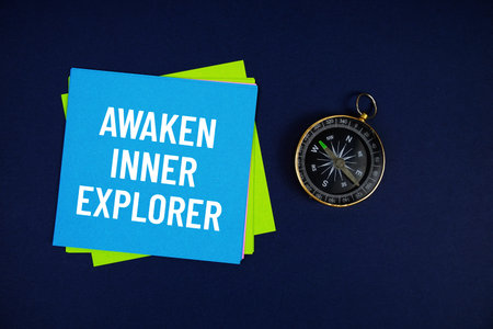 Awaken Inner Explorer text written on sticky note with compass on blue  background