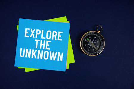 Explore The Unknown text written on sticky note with compass on blue  backgroundの写真素材