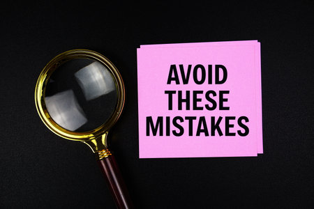 Avoid These Mistakes text on sticky note with magnifying glass on black backgroundの写真素材