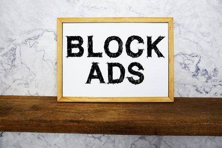 Block Ads text written on whiteboard with wooden shelf and marble backgroundの写真素材