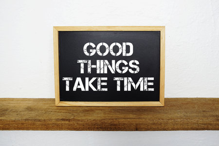 Good Things Take Time text written on blackboard with wooden shelf and concrete backgroundの写真素材