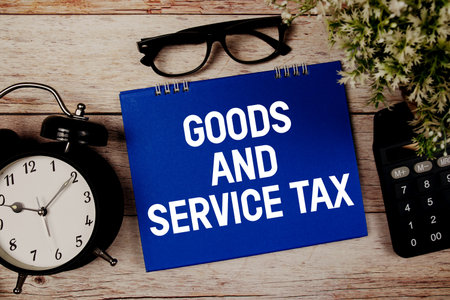 Goods and Service Tax text with alarm clock and calculator on wooden backgroundの写真素材