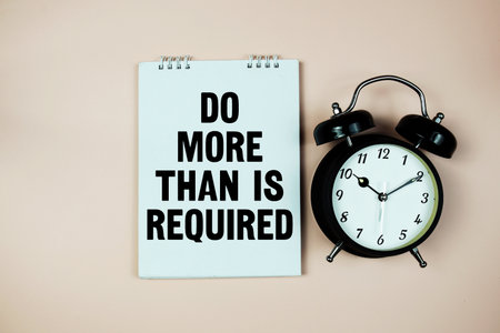Motivational Message with Alarm Clock "Do More Than Is Required" on pink backgroundの写真素材