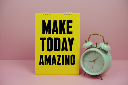 Motivational message "MAKE TODAY AMAZING" with green vintage alarm clock, set against a pink backgroundの写真素材