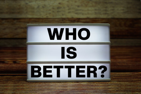 Lightbox with text "Who Is Better?" on wooden backgroundの写真素材