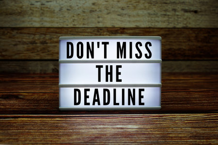 Lightbox with text "Don't Miss The Deadline" on wooden backgroundの写真素材