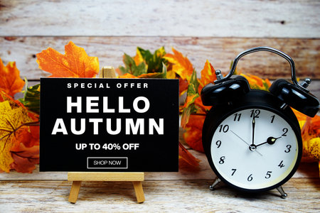 Hello Autumn Sale 40% off Special Offer text with alarm clock and maple leaf decoration on wooden backgroundの写真素材
