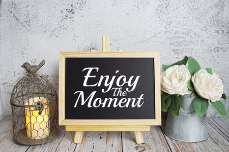 Enjoy the Moment text message on easel blackboard standing on wooden backgroundの写真素材
