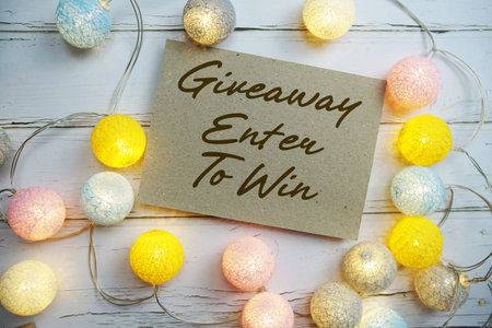 Giveaway Enter To Win text with gift present and LED cotton balls decorate on wooden background
