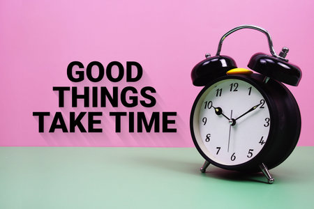 Black alarm clock on a pastel green and pink background with the text Good Things Take Time