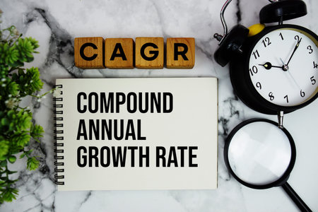 CAGR Compound Annual Growth Rate text with alarm clock and magnifying glass on marble background