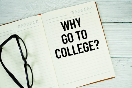 Notepad with message Why Go To College? and eyeglass on wooden background