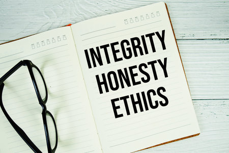 Notepad with message "Integrity, Honesty, And Ethics" and eyeglass on wooden backgroundの写真素材
