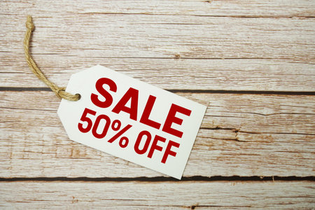 Price tag with "Sale 50% Off" is placed on wooden backgroundの写真素材