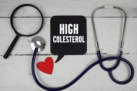 High Colesterol text with Red heart, Magnifying glass and Medical Stethoscope on wooden backgroundの写真素材