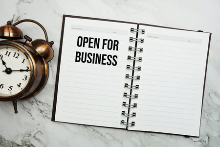 Open For Business text written on notepad with alarm clockの写真素材