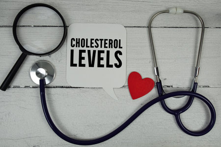 Cholesterol Levels text with Red heart, Magnifying glass and Medical Stethoscope on wooden backgroundの写真素材