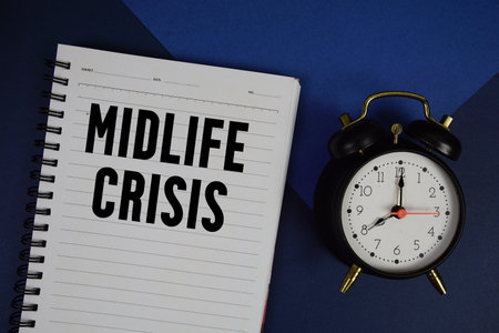 Midlife Crisis text written on notepad with alarm clock on navy blue backgroundの写真素材