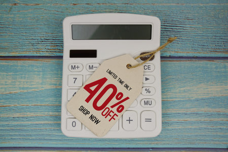 Sale 40% off Shop Now with price tag and calculator on wooden backgroundの写真素材