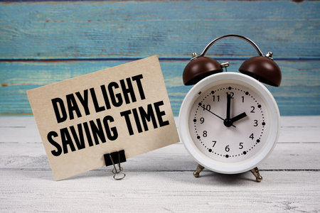 Daylight Saving Time  text written on paper card with alarm clock on wooden backgroundの写真素材