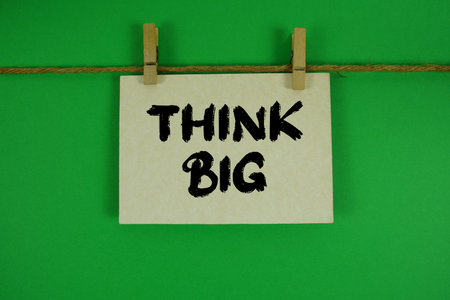 Think Big text written on paper card with rope and wooden clip hanging