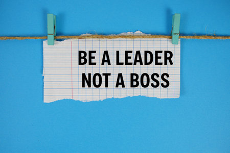 Be A Leader Not A Boss text written on rip paper with wooden clip on blue background