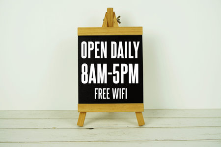 Wooden blackboard easel with text Open Daily 8am-5pm on wooden background