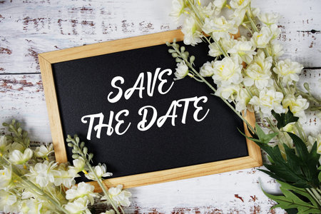 Save The Date text with flowers decoration on wooden background