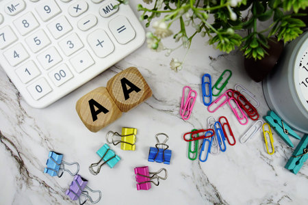 AA (Affirmative Action) alphabet letters with calculator and alarm clock on marble background