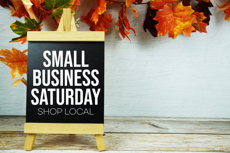 Small Business Saturday Shop Local text with maple leaf decoration on wooden background