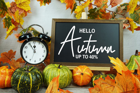 Autumn Sale 40% text with alarm clock and maple leaf decoration on wooden background