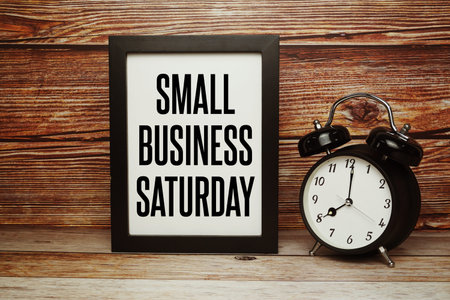 Small Business Saturday text with alarm clock on wooden background