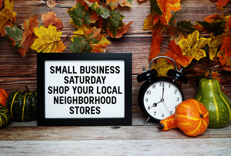 Small Business Saturday Shop Your Local Neighborhood Stores text with alarm clock on wooden background