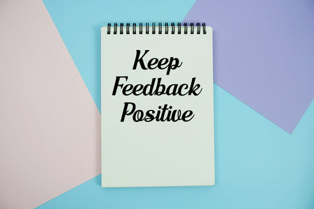 Keep Feedback Positive text written on notepad flat lay on multicolor pastel background