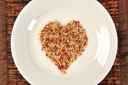 Brown rice grains in the form of heart on bowlの写真素材