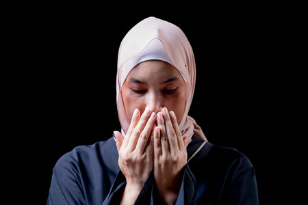 The image of an Asian Muslim woman in the Islamic religion in hijab in cream and black color. She was praying in a beautiful mosque out of respect for God.の写真素材