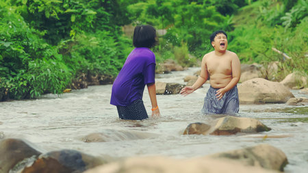 Children playing with friends in the river in the countryside, Boys and girls smiling and happy playing water in the countryside in Thailand.の写真素材