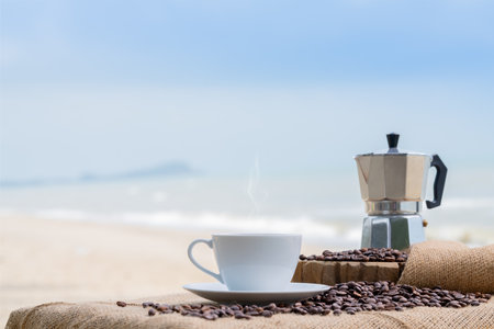Close-up white coffee cup and many coffee beans placed around on the wood table with a beautiful seascape of nature background, concept coffee vacation travel.の写真素材